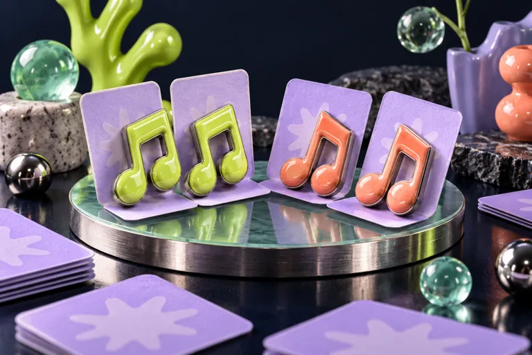 Conceptual miniature illustration: two matching pairs of sculptural musical note tokens revealed from lilac cards.